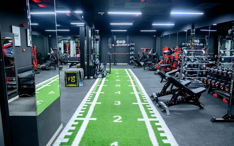 Elevate gym in Madinat Qaboos, Muscat &mdash; turf lane, dumbbell rack and red resistance machines in the private studio