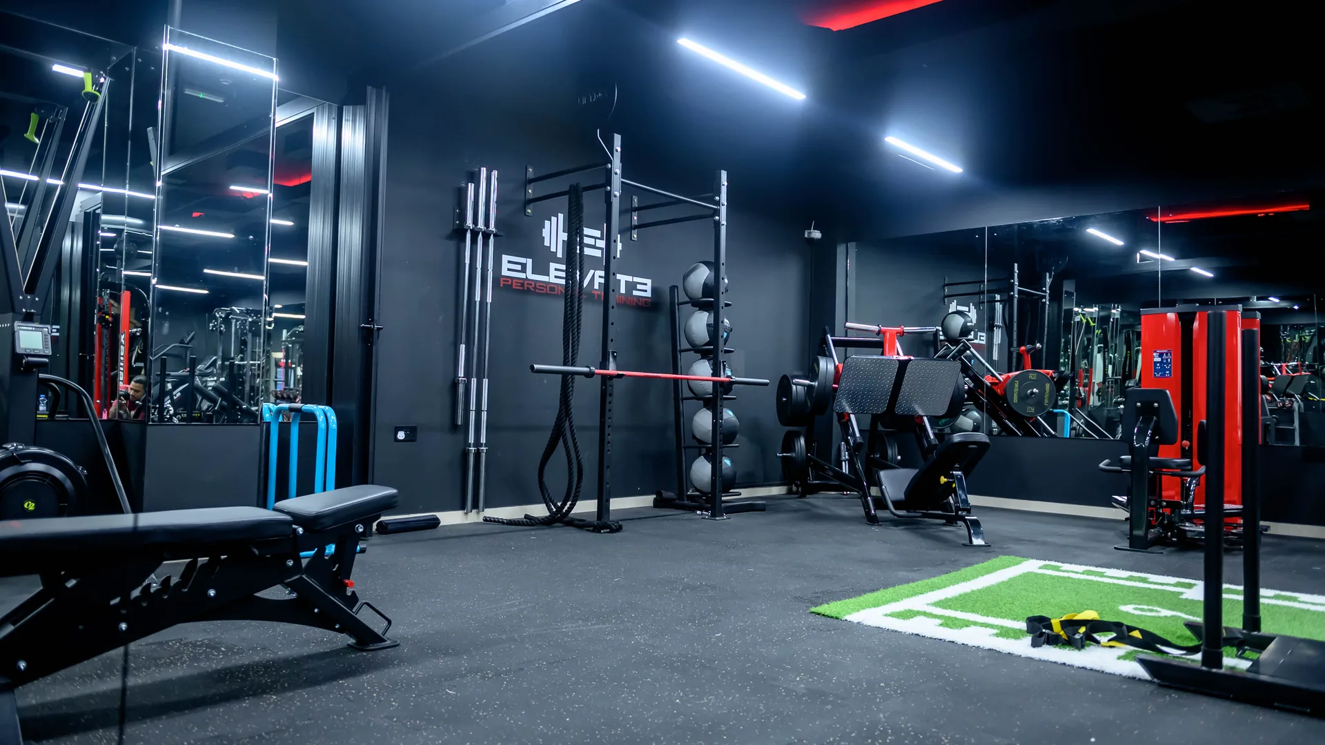 Training floor at the Elevate studio in Madinat Qaboos with branded wall, benches and red machines