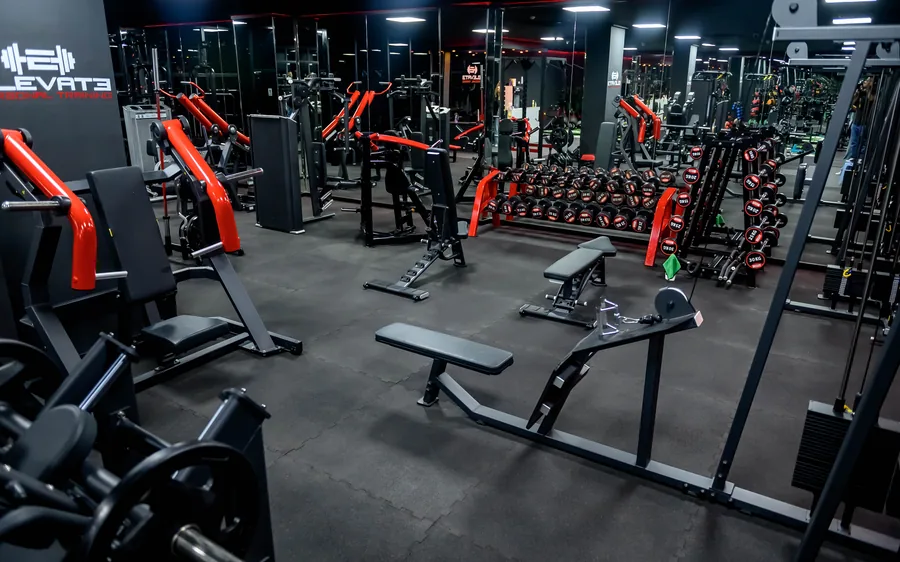 Elevate personal training studio in Muscat &mdash; red-trimmed lat pulldown and racked equipment under the Elevate sign