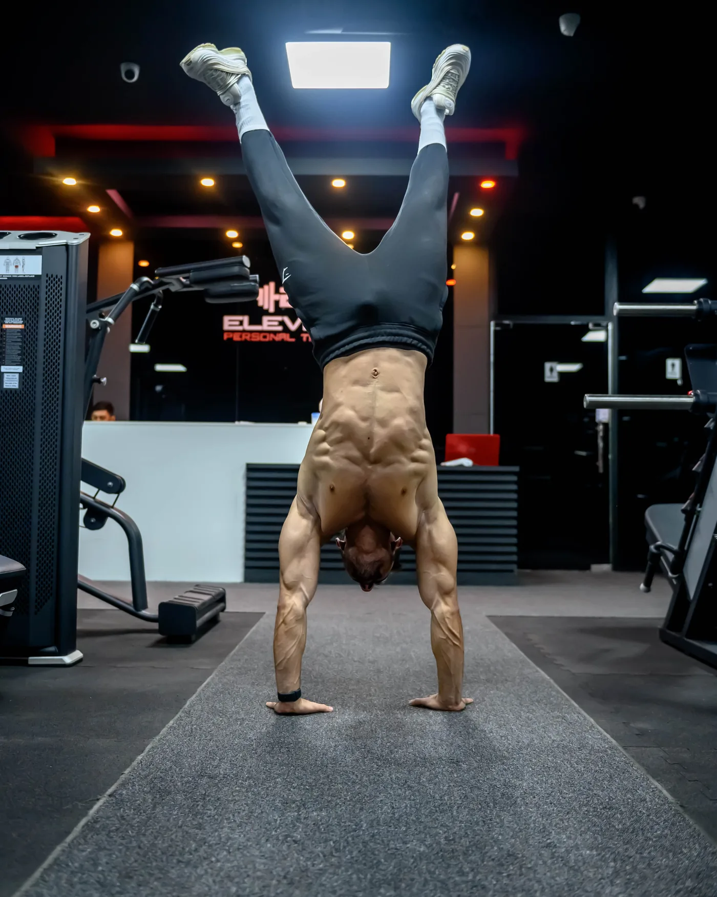 Al Khuwair 4 Handstand on the studio floor at Elevate Al Khuwair, Muscat, with the Elevate sign behind