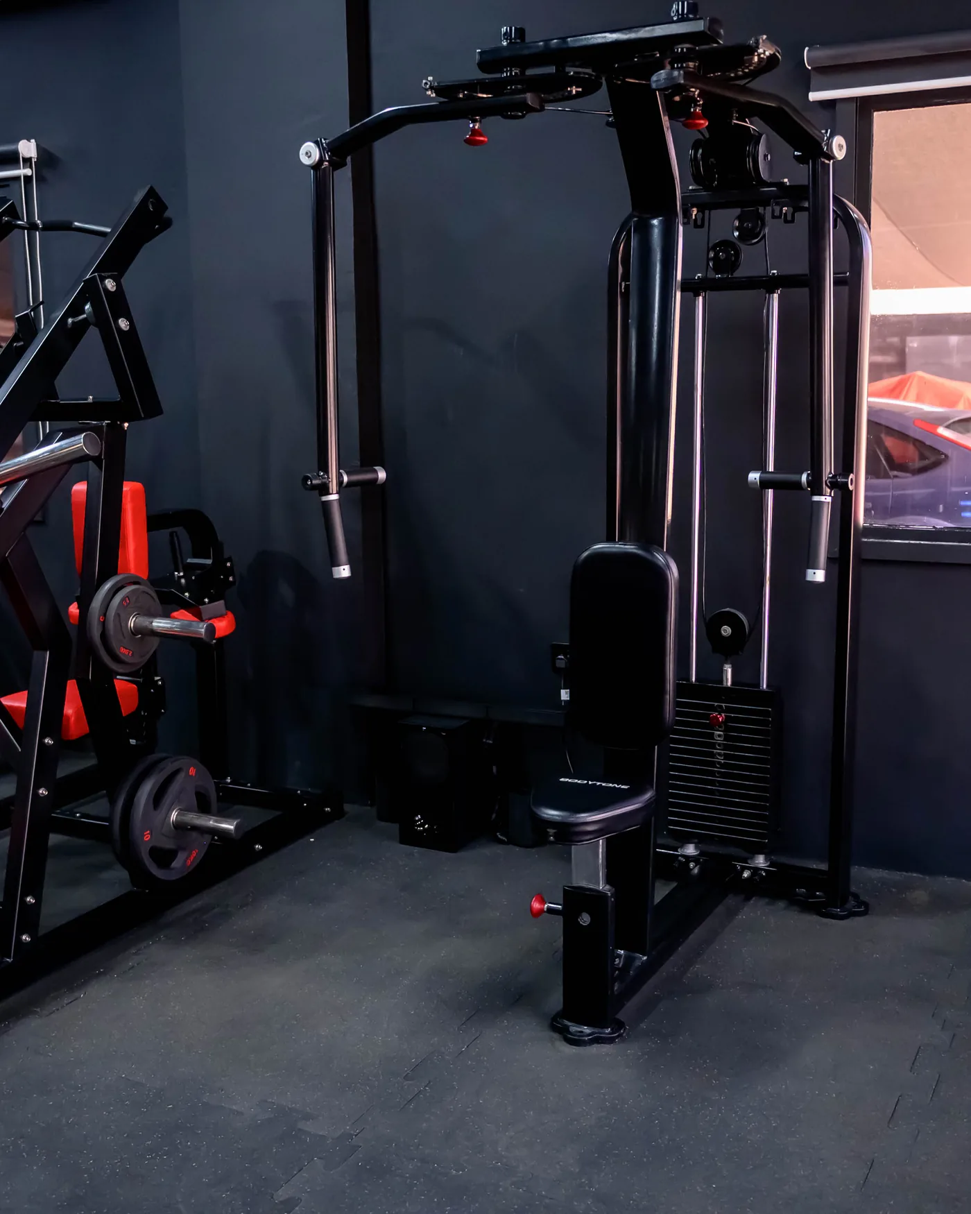 Azaiba Ladies 3 Red plate-loaded machines beside the window in the Elevate ladies-only studio, Azaiba